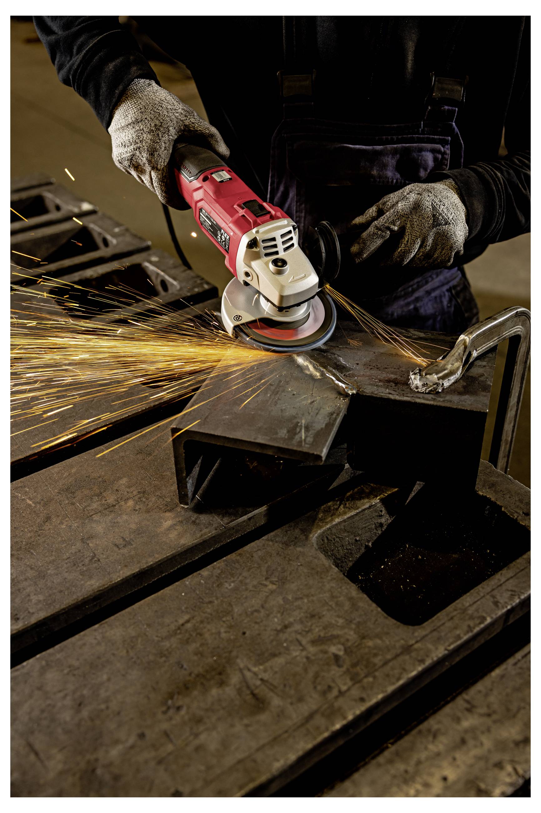 Arbeiter, der einen Winkelschleiffer auf einem Metallwerkstück verwendet und helle Funken über eine Werkstattbank sendet.