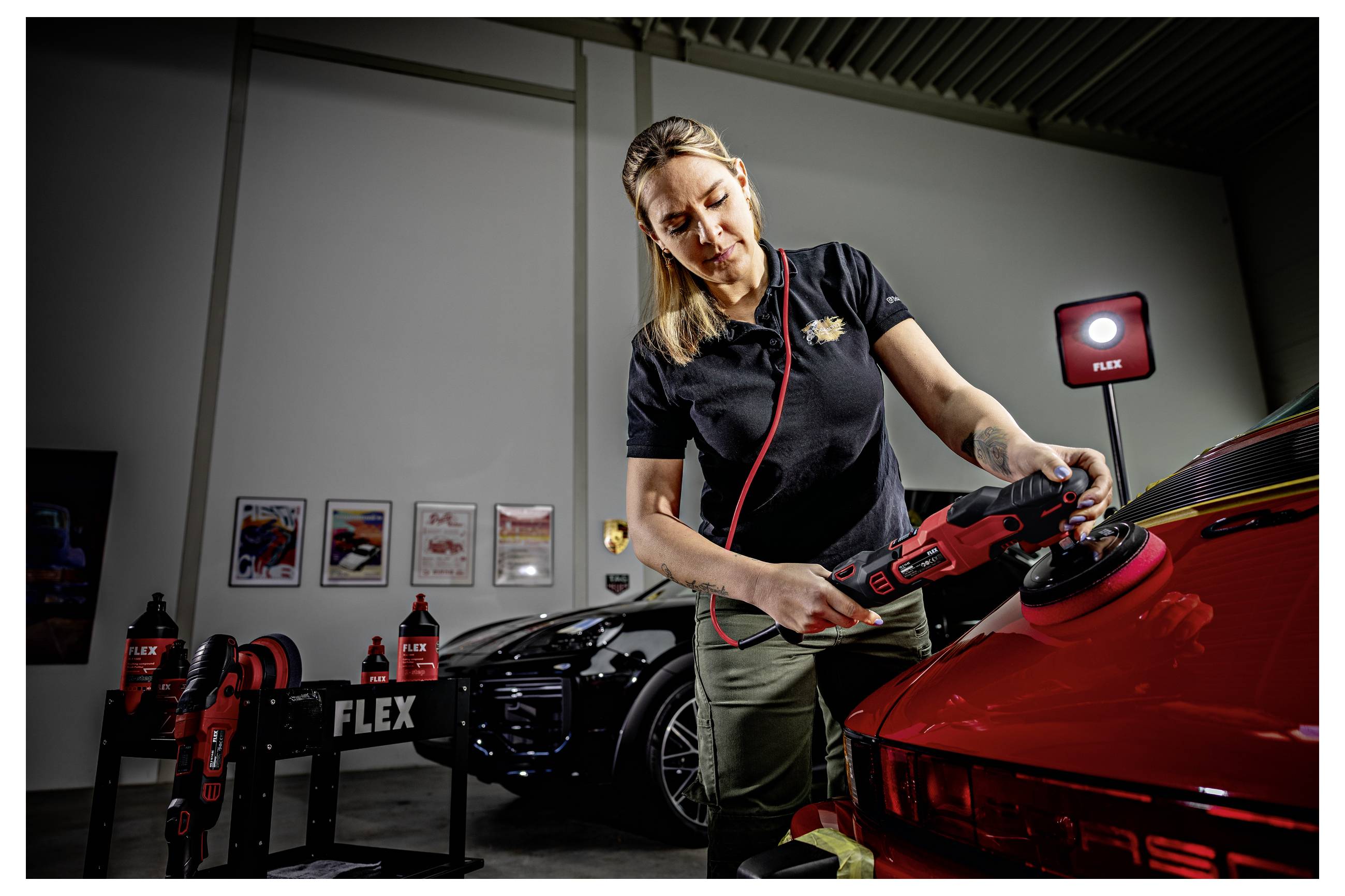 Frau verwendet ein rotes FLEX Elektroschleiferpoliergerät an einem roten Sportwagen in einer Garage, mit Elektrowerkzeugen und Autopflegeprodukten in der Nähe ausgestellt.