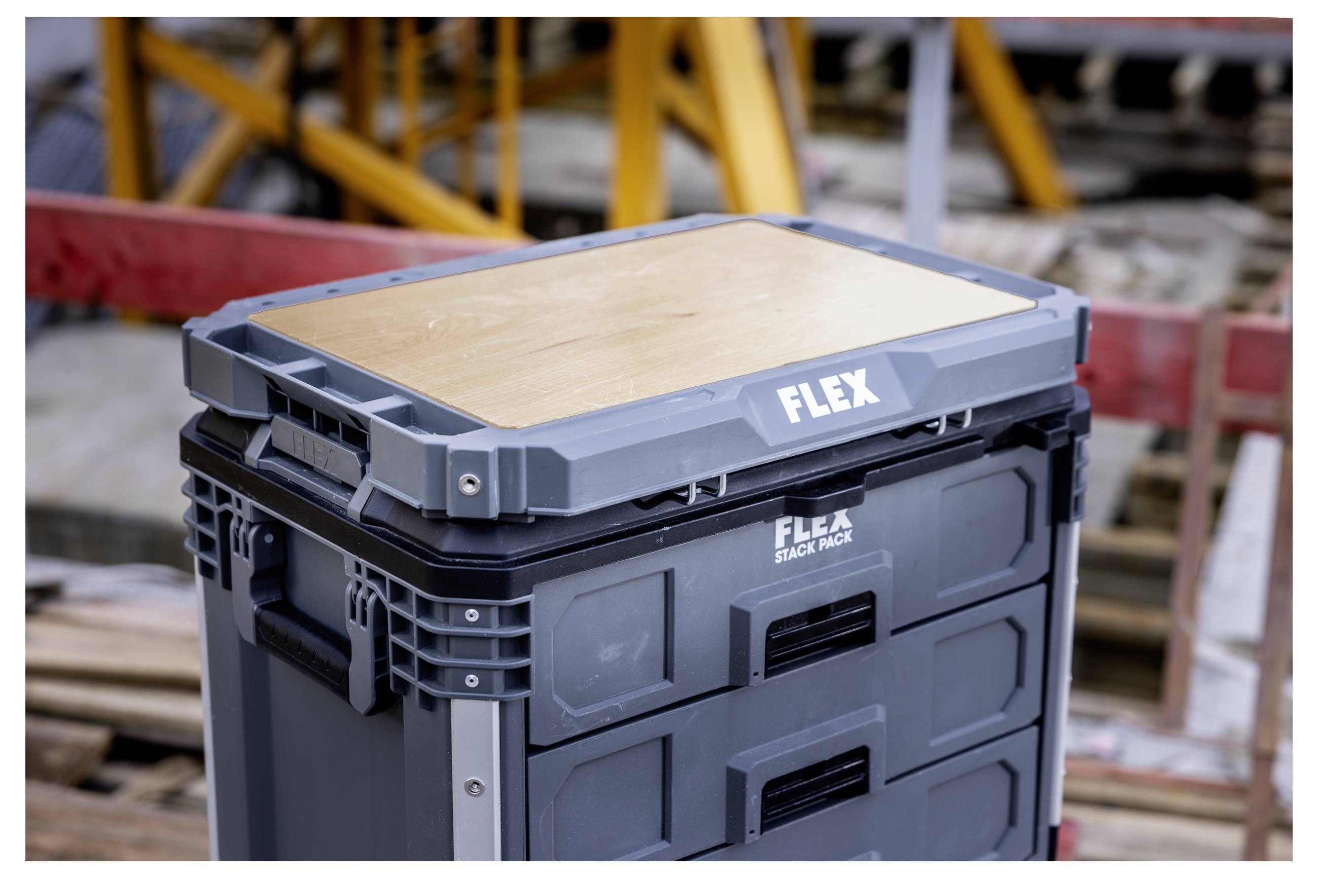 Gestapelte FLEX-Werkzeugspeicherbox auf einer Baustelle, mit Holzoberseite und grau verschließbaren Schubladen mit der Aufschrift „FLEX