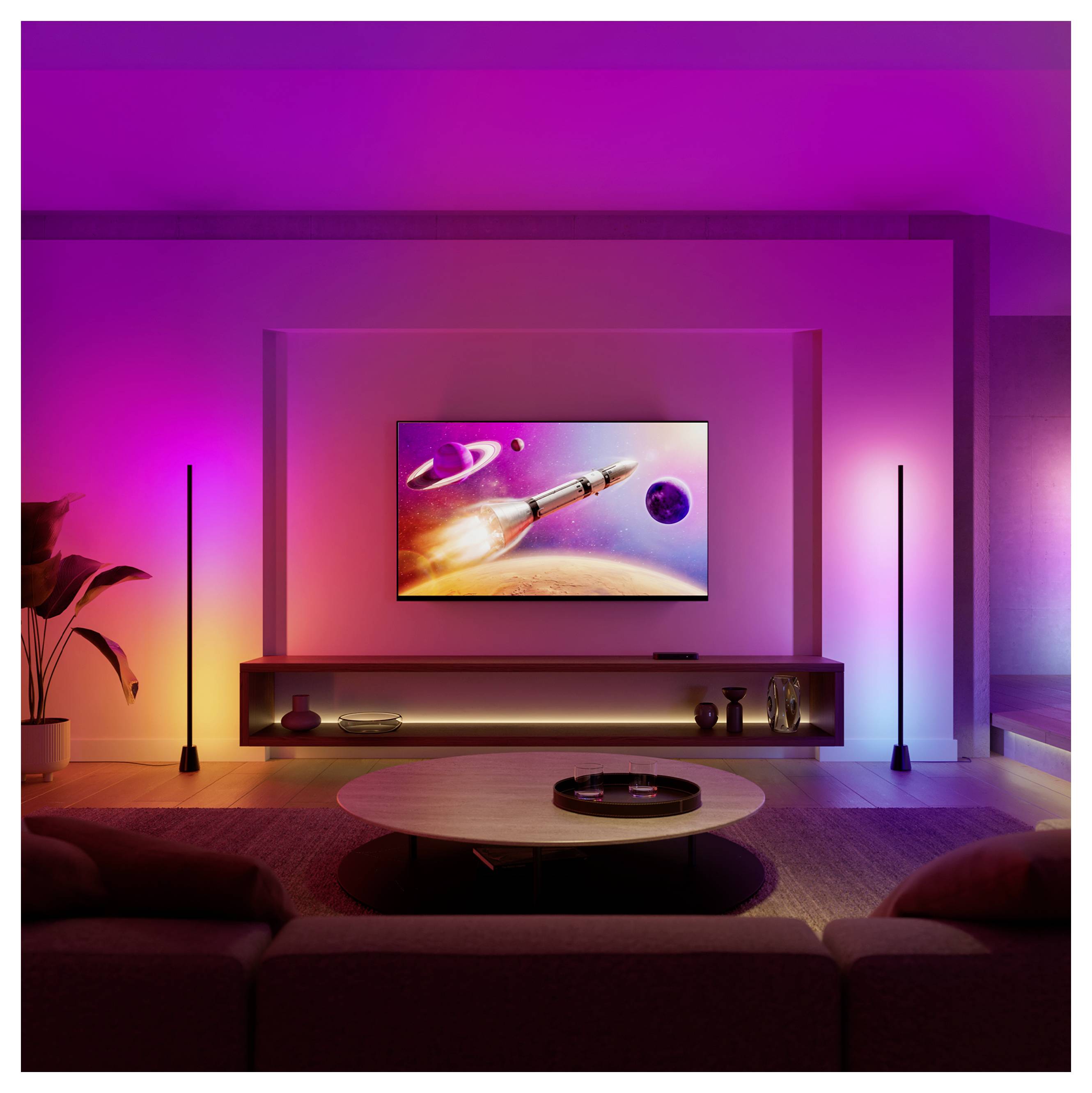 Modernes Wohnzimmer mit an der Wand montiertem Fernseher, der einen Raketenstart im Weltall zeigt, beleuchtet durch farbenfrohe rosa, lila und blaue Umgebungsbeleuchtung.