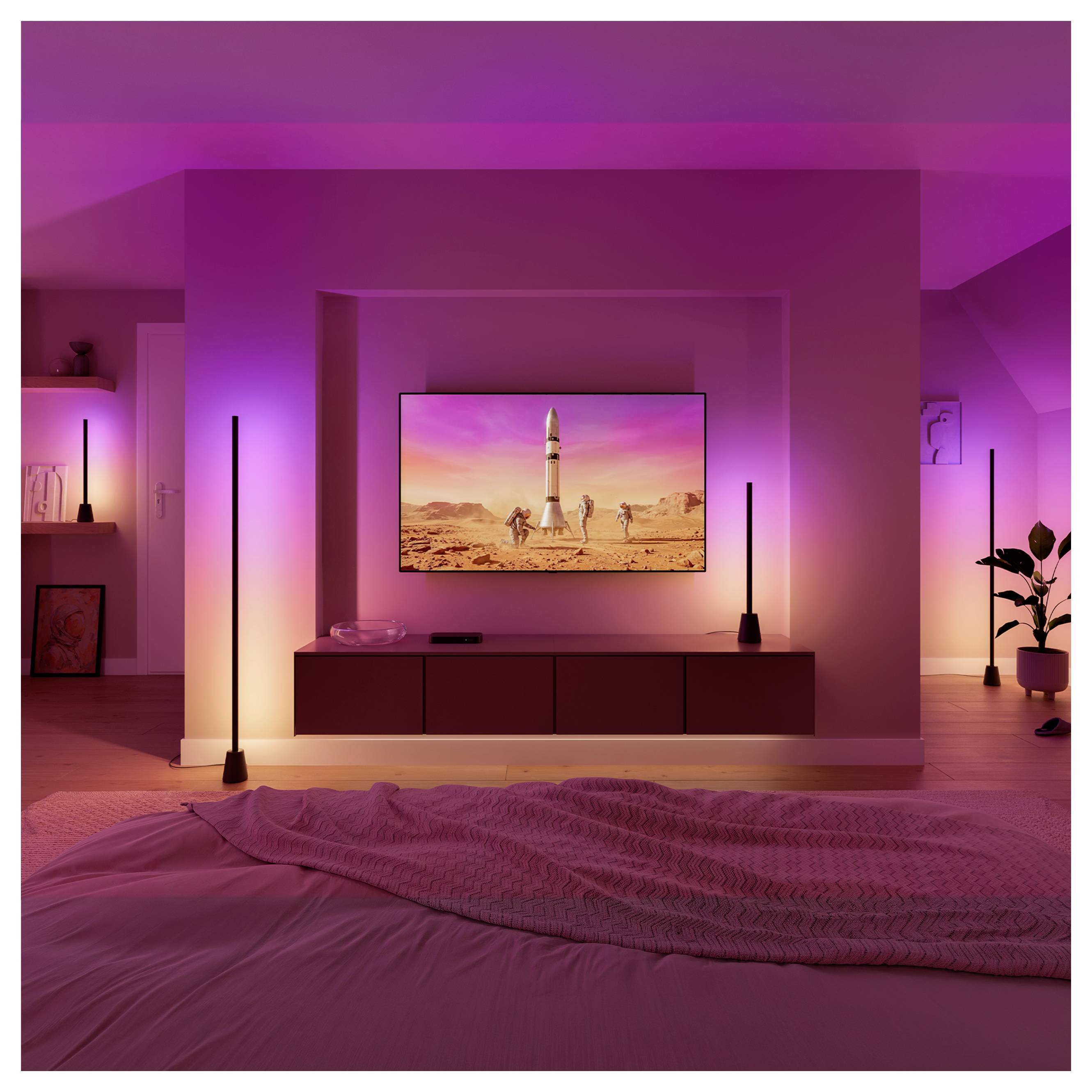 Modernes Schlafzimmer mit violetter Umgebungsbeleuchtung, an der Wand montiertem Fernseher, der eine Rakete auf einem Startplatz in der Wüste zeigt, Stehlampen und einem Bett im Vordergrund.