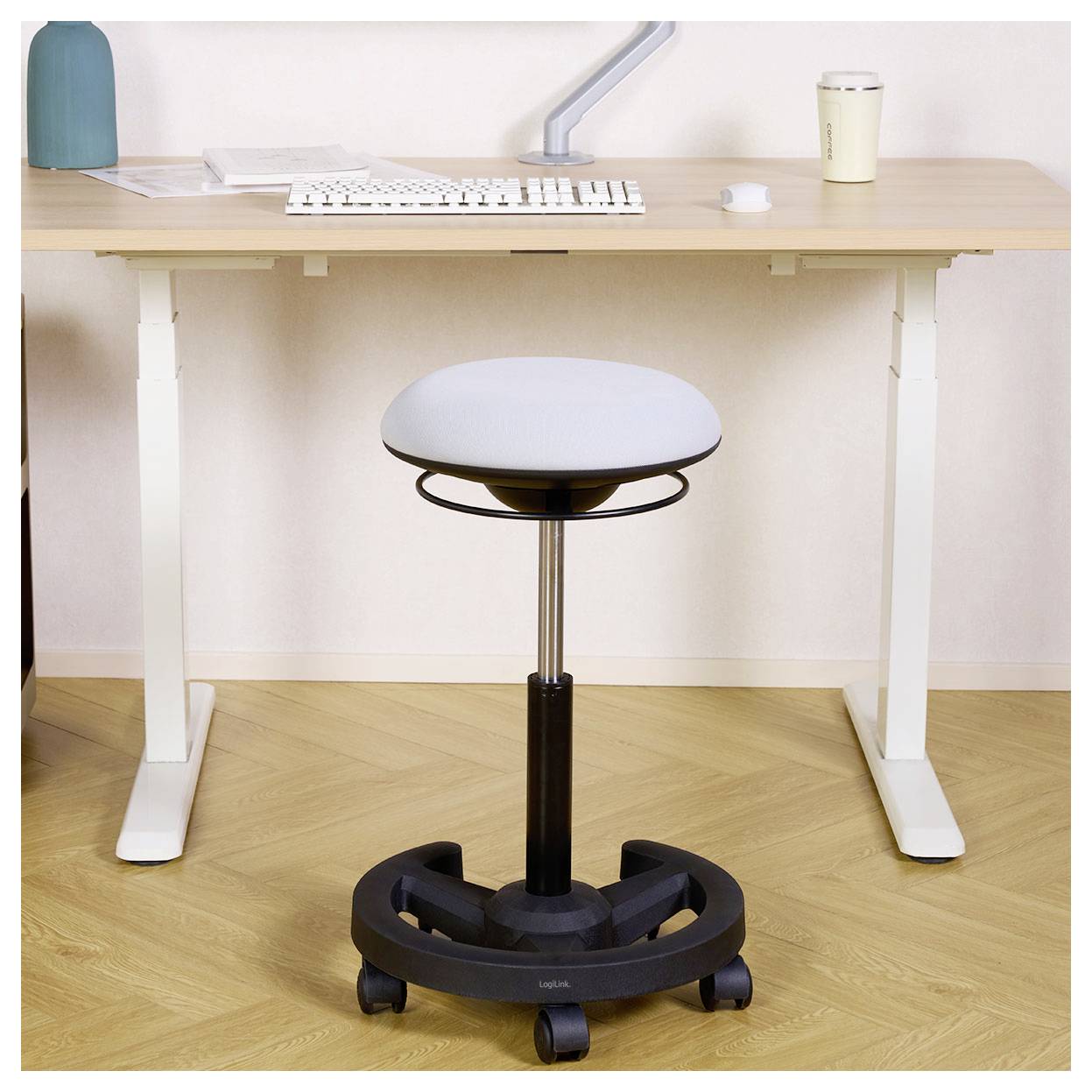 Höhenverstellbarer Hocker auf Rollen, zentriert unter einem Stehschreibtisch in einem minimalistischen Homeoffice.