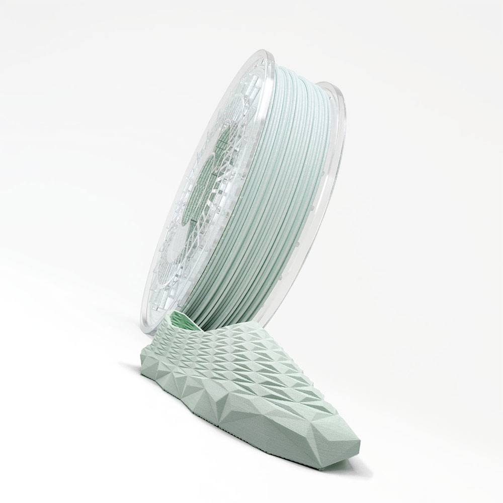 Spule aus mintgrünem Filament, das in einen 3D-gedruckten geometrischen Sockel auf weißem Hintergrund führt.