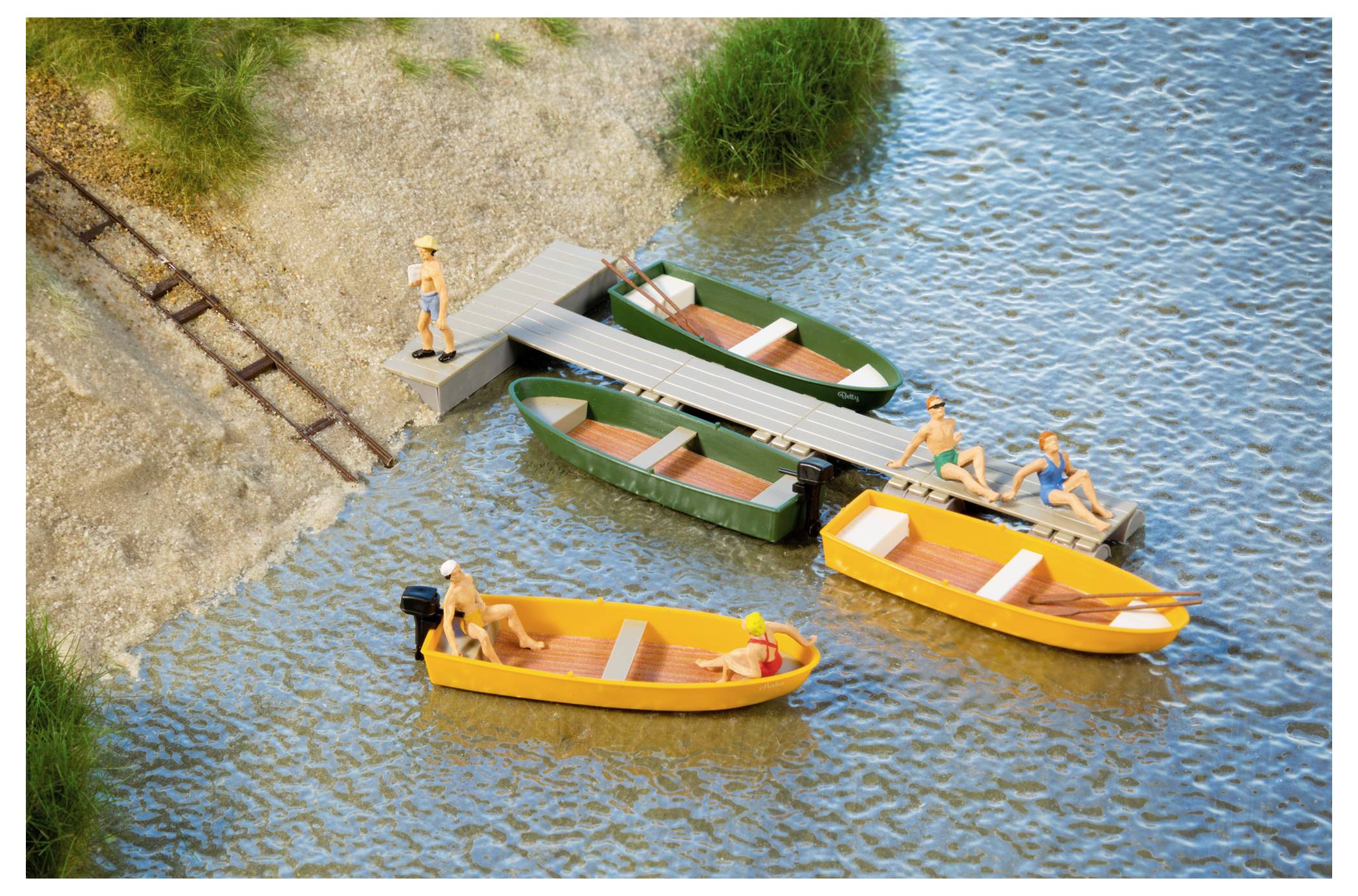 Miniaturlandschaft am See mit kleinen Booten, die an einem Steg vertäut sind, und winzigen Figuren, die sich entspannen, eine Person steht auf dem Steg und weitere sind in den Booten.