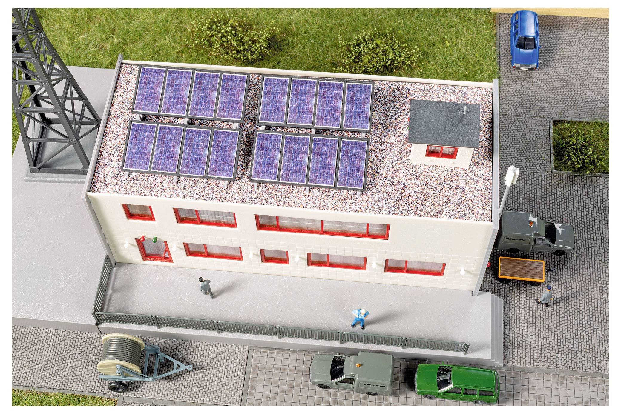 Modellgebäude mit Dachsolaranlagen, umgeben von Straßen und geparkten Fahrzeugen, aus der Vogelperspektive betrachtet.