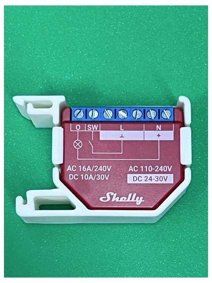 Shelly-Relaismodul auf grünem Hintergrund, mit Schraubklemmen mit den Bezeichnungen O, SW, L und N sowie Leistungsangaben AC 16A/240V, DC 10A/30V, AC 110-240V und DC 24-30V.