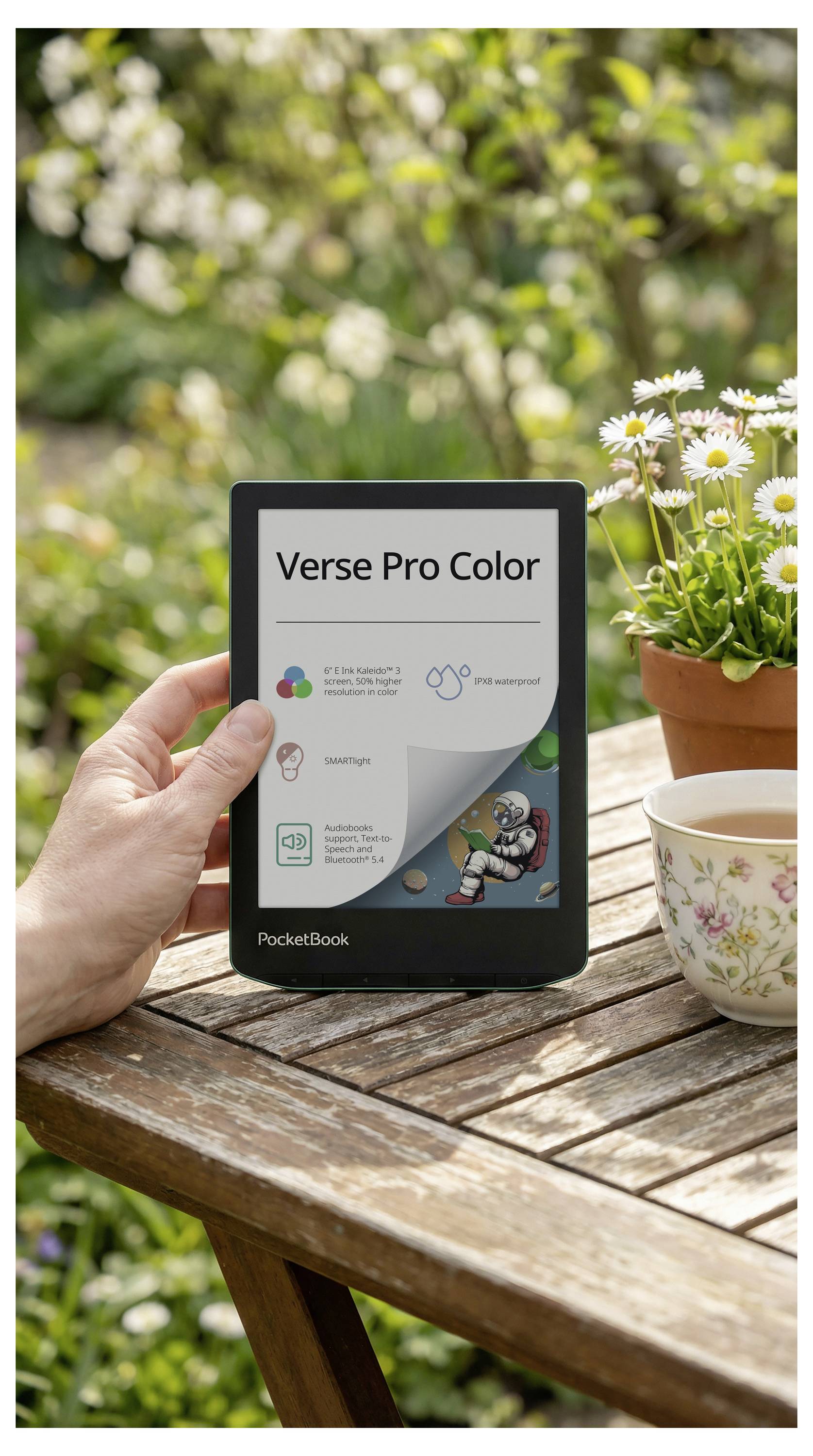 Hand, die einen PocketBook-E-Reader auf einem Gartentisch hält; der Bildschirm zeigt „Verse Pro Color