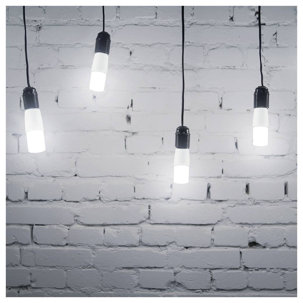 Vier hängende, leuchtende Glühbirnen vor einer weiß gestrichenen Backsteinmauer.