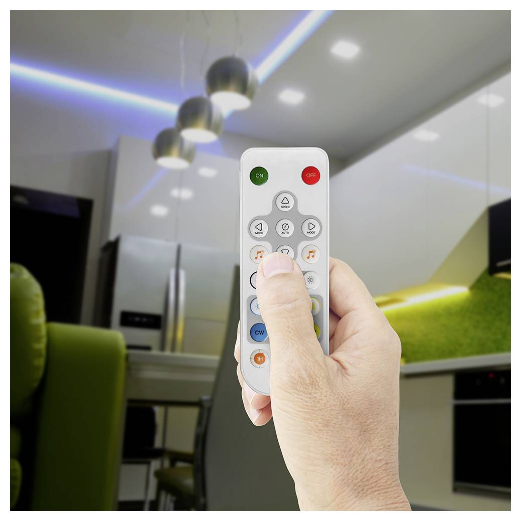 Hand drückt eine Fernbedienung, um Deckenleuchten in einer modernen Küche einzustellen, mit sichtbarer farbiger LED-Akzentbeleuchtung über den Schränken.