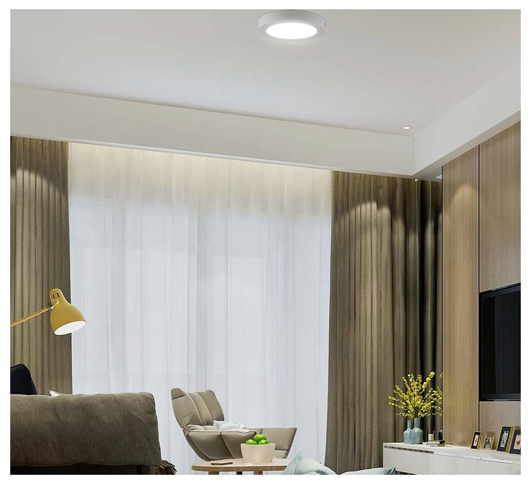 Modernes Wohnzimmer mit transparenten Vorhängen, beigem Relaxsessel, Stehleuchte, Fernsehschrank und kleinen gelben Blumen am Fenster.
