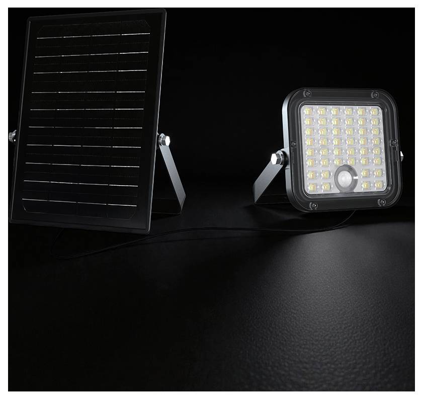 Solar-betriebenes LED-Flutlicht mit separatem Solarpanel auf einer schwarzen Oberfläche vor dunklem Hintergrund.