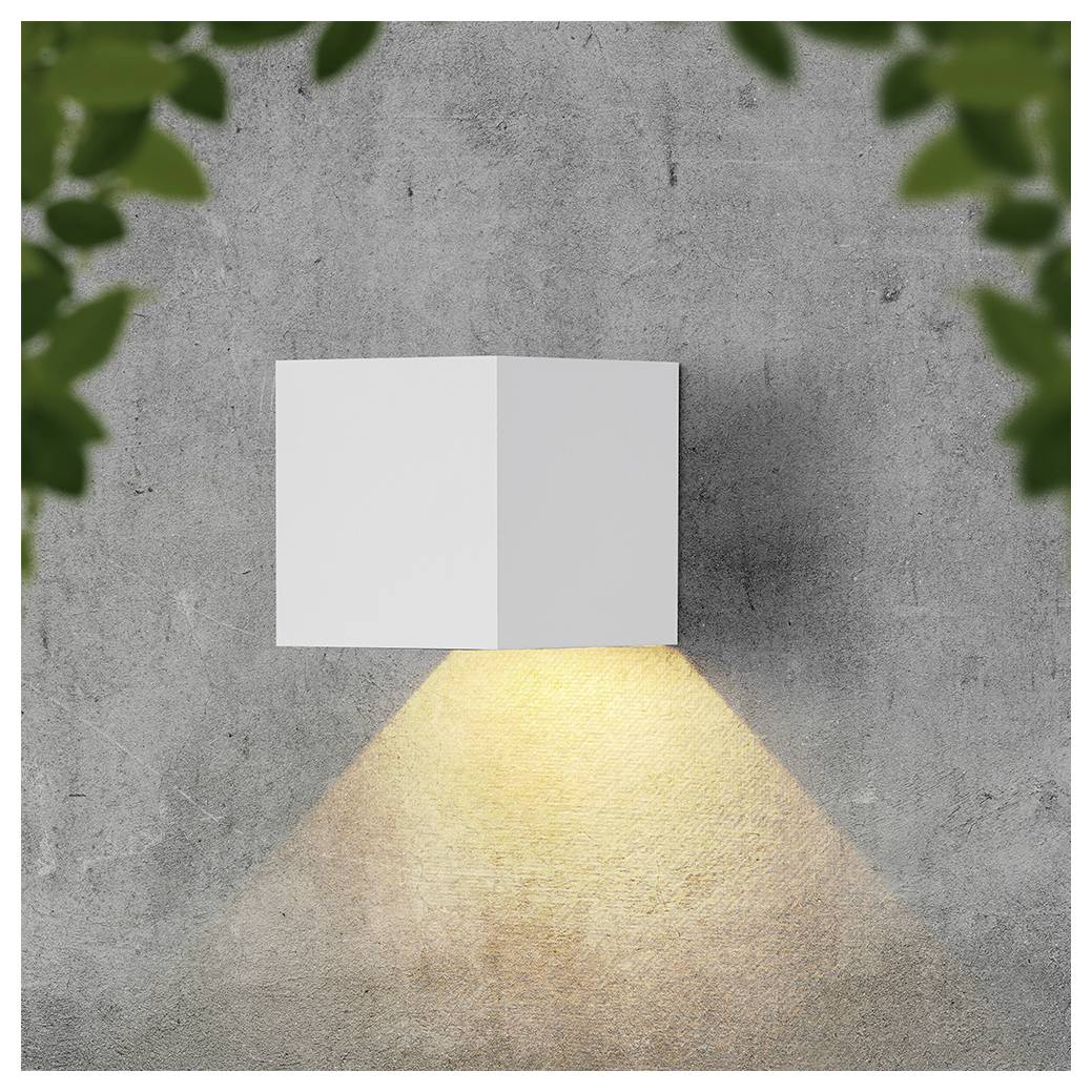 Moderne weiße Wandleuchte, die einen warmen dreieckigen Lichtstrahl auf eine graue Betonwand wirft, eingefasst von unscharfen grünen Blättern in den Ecken.