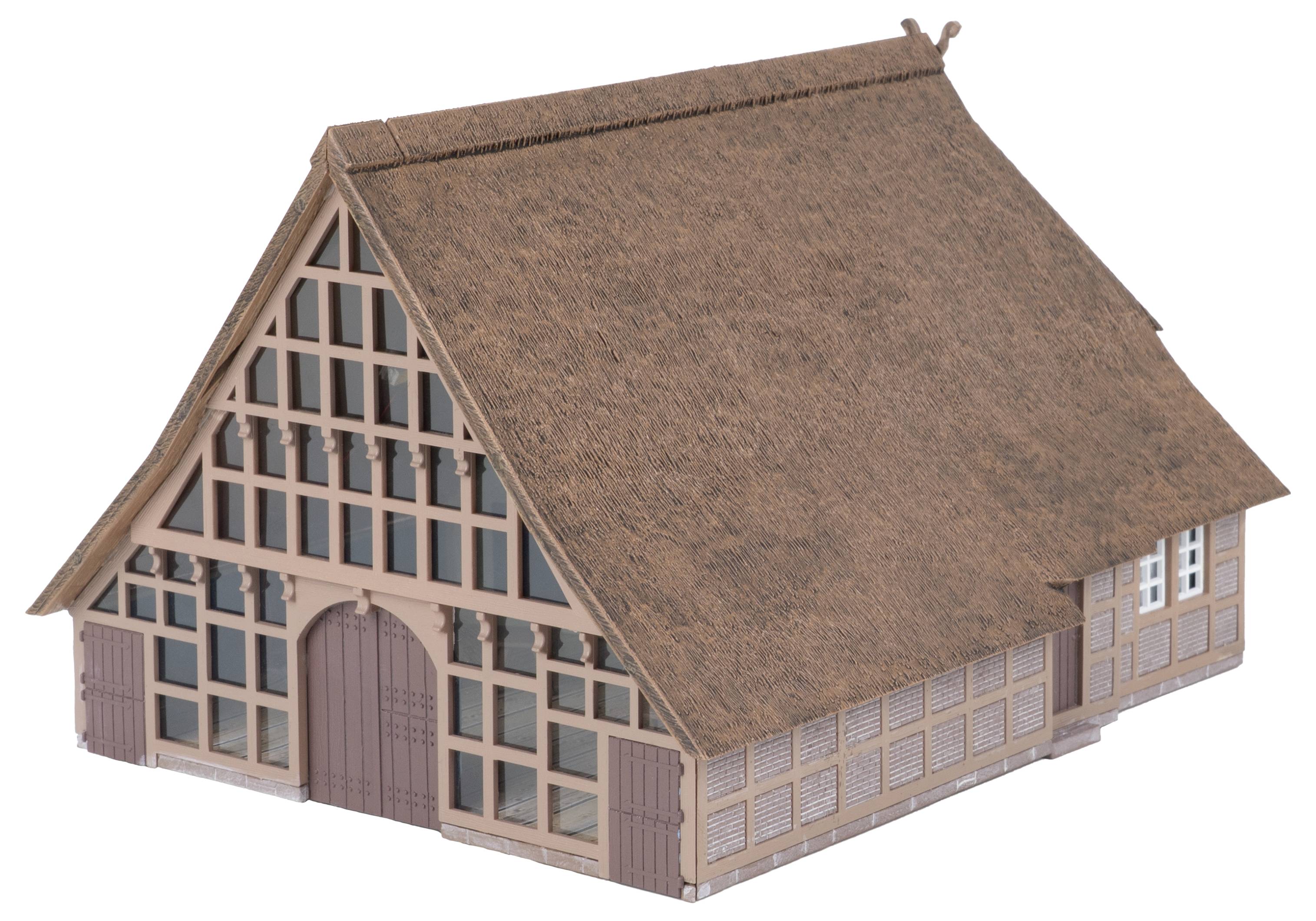 Ein kleines Modell eines Holzhauses mit Strohdach, steilen Giebeldach und gitterförmig gemusterter Frontfassade.