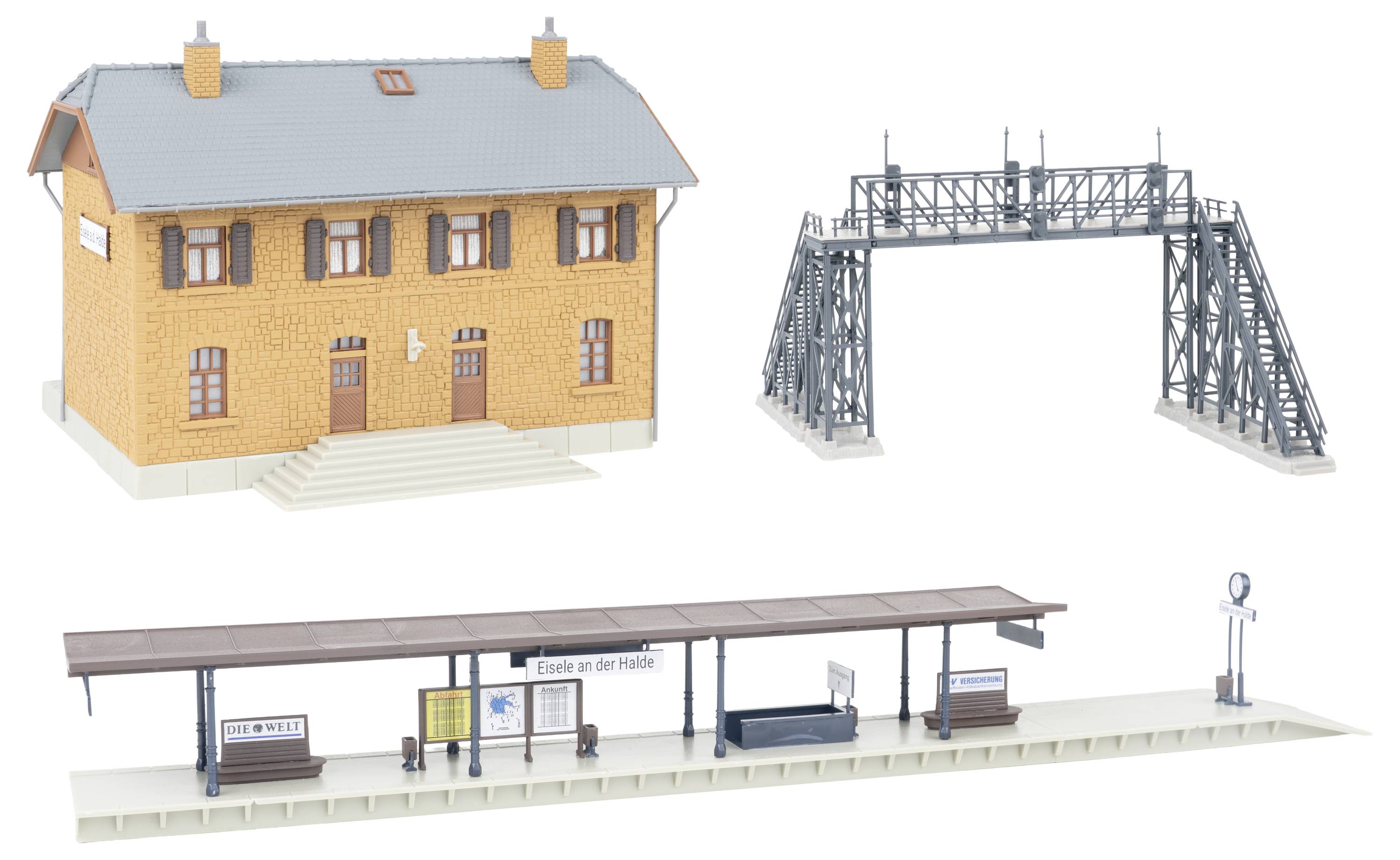 Modelleisenbahnszene mit einem Backsteinbahnhofsgebäude, einer Metallsignalbrücke und einem überdachten Bahnsteig mit Bänken, Schildern und Bahnhofsuhr.
