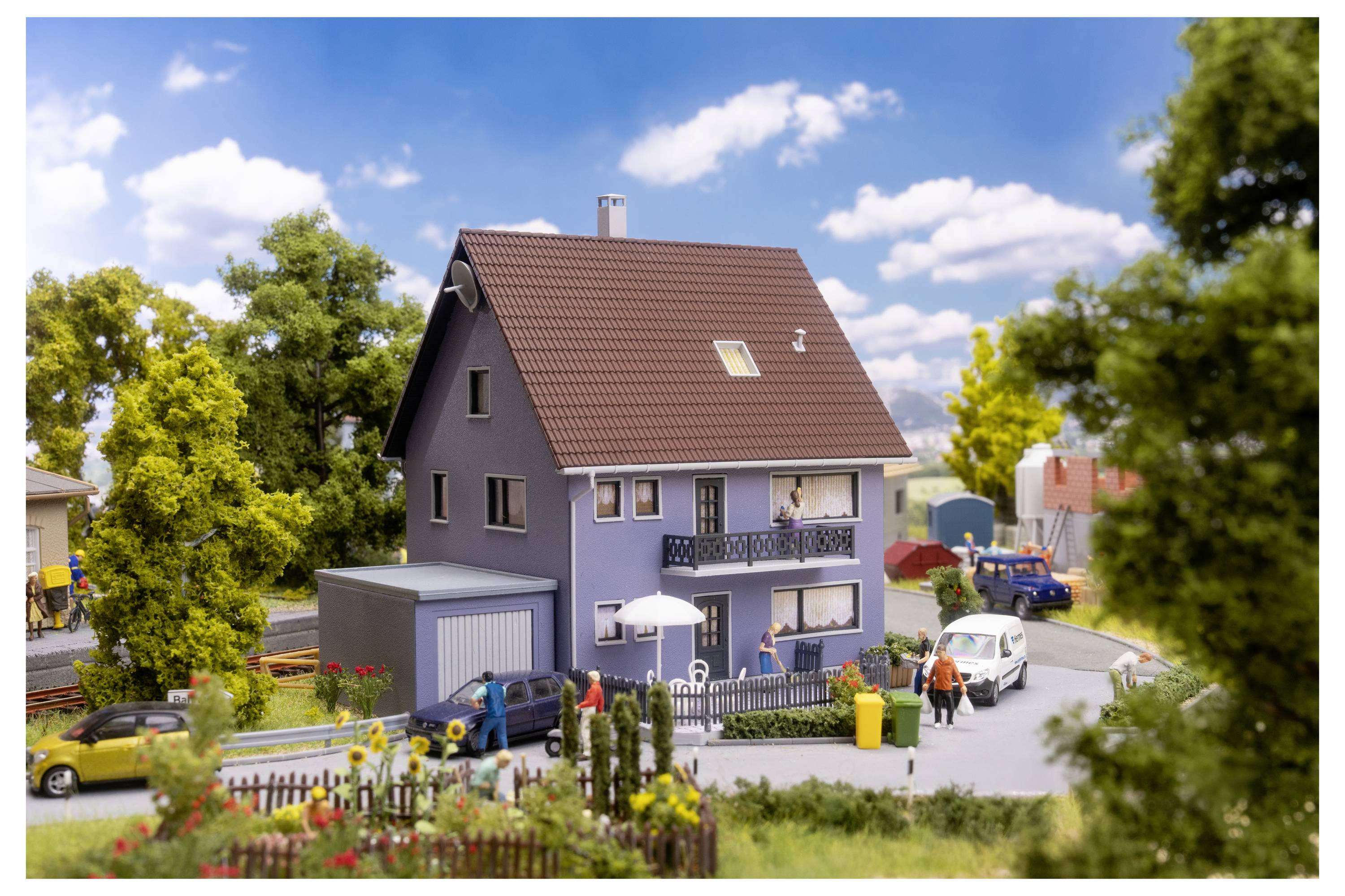 Modellhausszene mit Personen, Autos und Bäumen in einer landschaftlich gestalteten Nachbarschaft