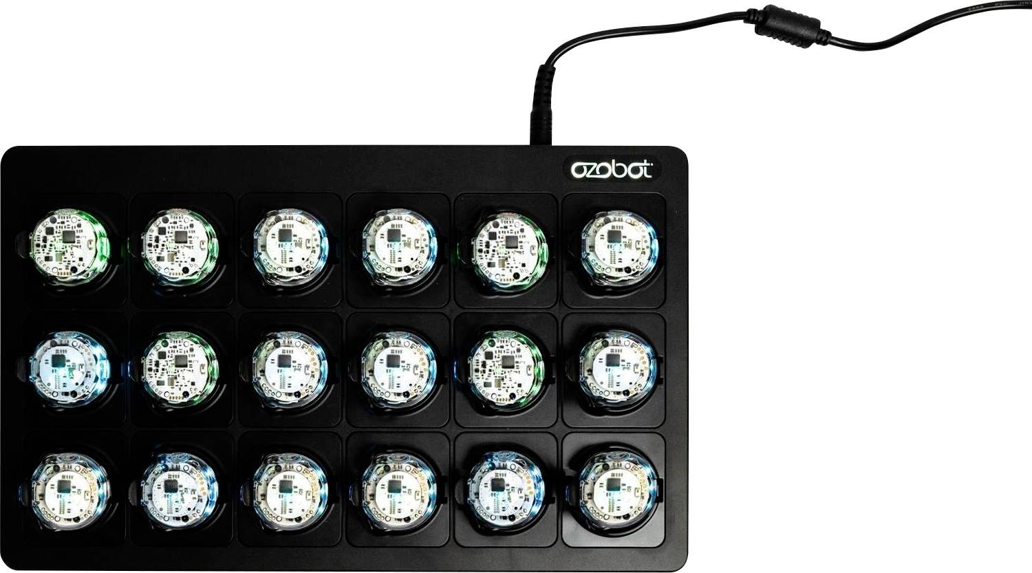 Ein schwarzes Ozobot-Ladedock fasst 15 kleine runde Roboter in einem 3-mal-5-Raster und ist oben durch ein Stromkabel verbunden.