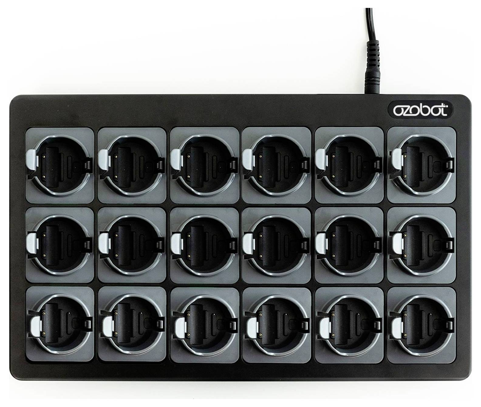 Schwarzes Ozobot-Ladedock mit 18 runden Steckplätzen, die in 3 Reihen angeordnet sind, von oben abgebildet mit angeschlossenem Stromkabel.