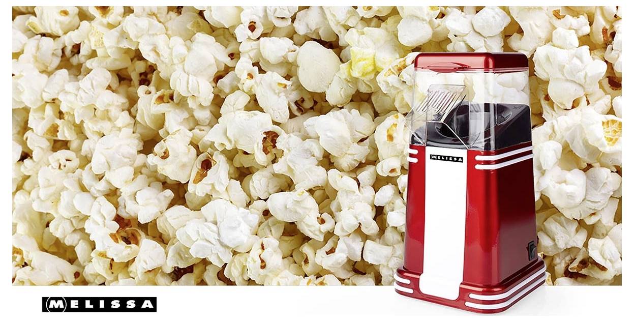 Eine rot-weiße Popcornmaschine sitzt vor einem unscharfen Hintergrund aus Popcorn, mit dem Markennamen 