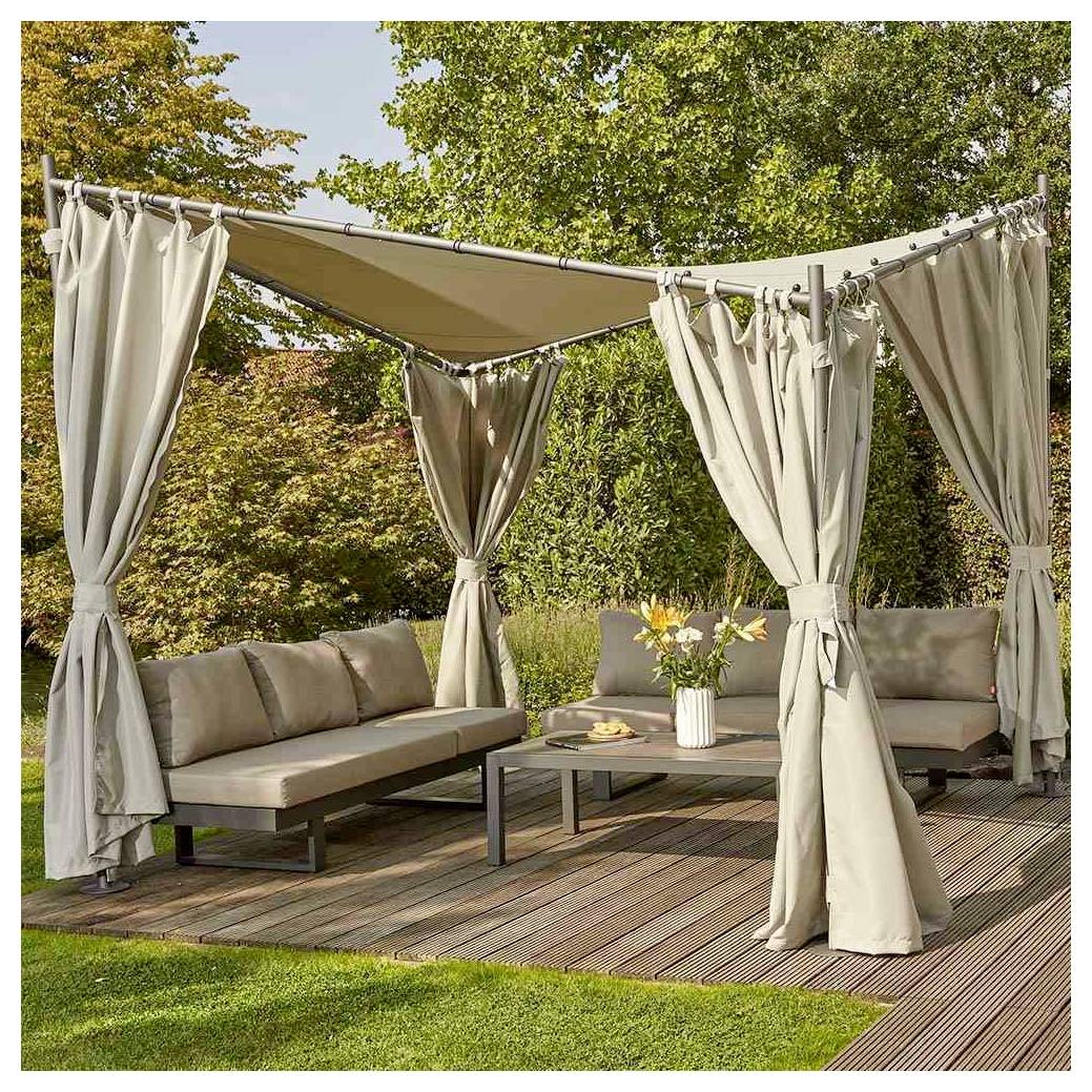 Outdoor-Terrassenpavillon mit beigen Vorhängen, Eckgarnitur und Couchtisch auf einem Holzdeck in einem Garten.