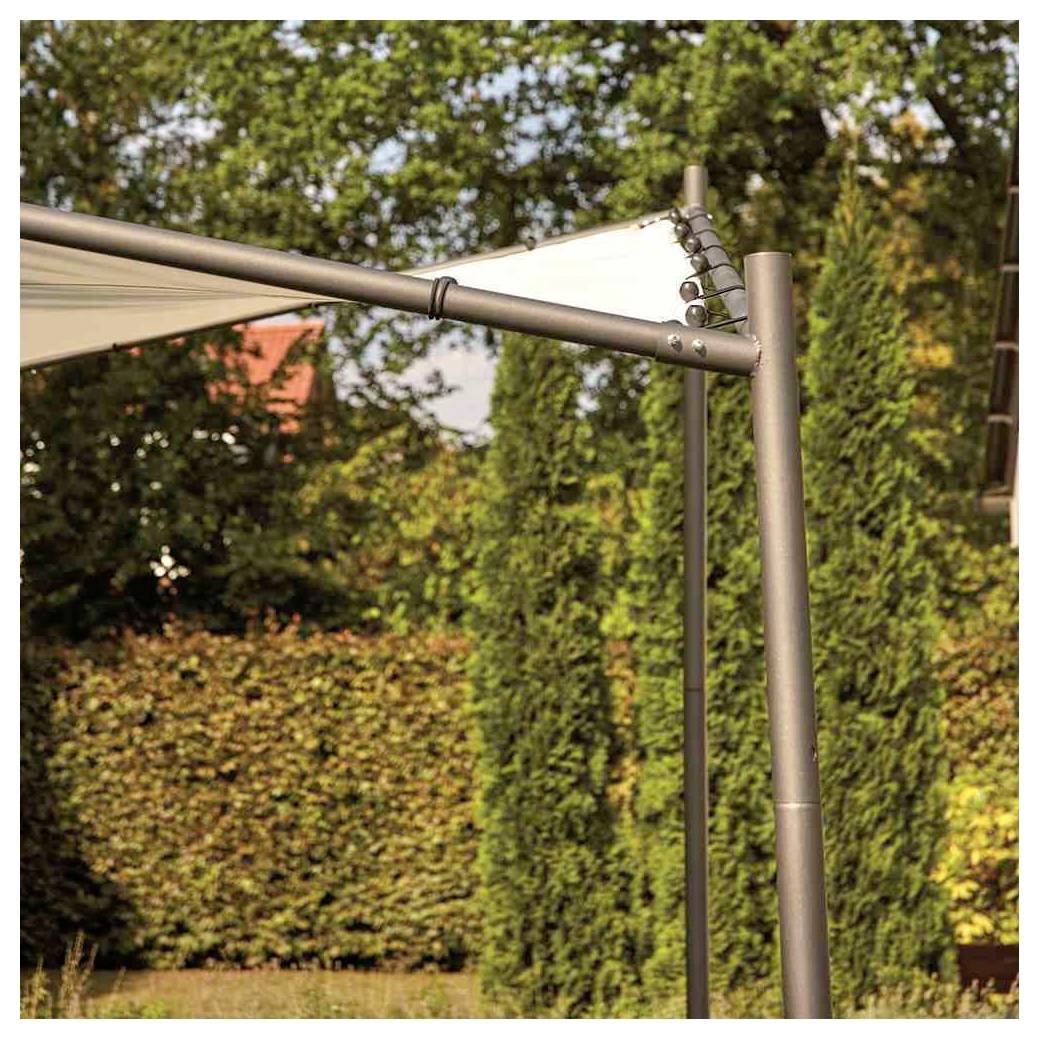 Nahaufnahme eines grauen Metallrahmens für ein Sonnensegel mit Kabeln und Pfosten, aufgestellt in einem sonnigen Garten mit Bäumen und Hecken.