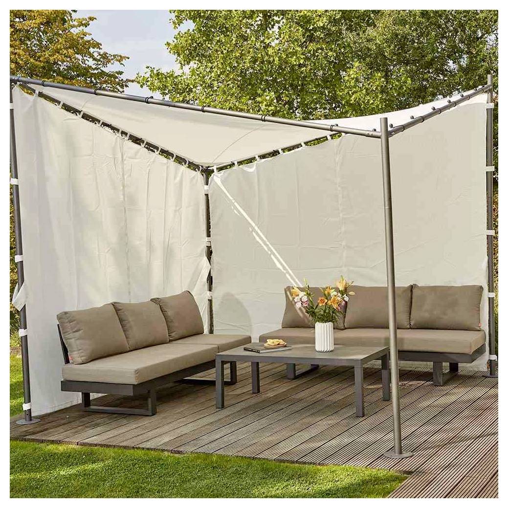Outdoor-Lounge-Bereich mit zwei beigen Sofas, Couchtisch und weißen Sichtschutzvorhängen unter einem Vordach, angebracht auf einer Holzterrasse.