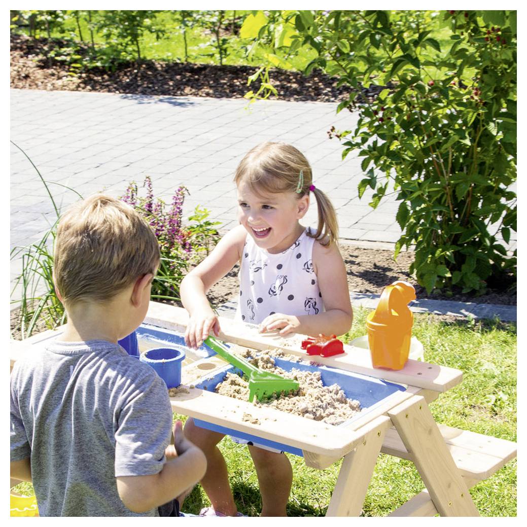 Zwei Kinder spielen mit Sand an einem Sinnesspielplatz im Freien in einem sonnigen Garten und benutzen Werkzeuge und Eimer.