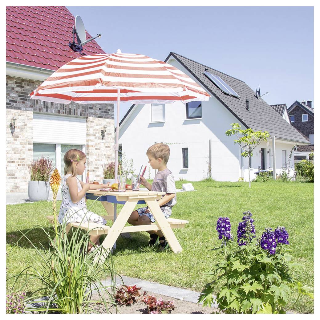 Zwei Kinder sitzen an einem Picknicktisch unter einem rot-weiß gestreiften Schirm in einem sonnigen Garten der Vorstadt mit Häusern und Blumen in der Nähe.