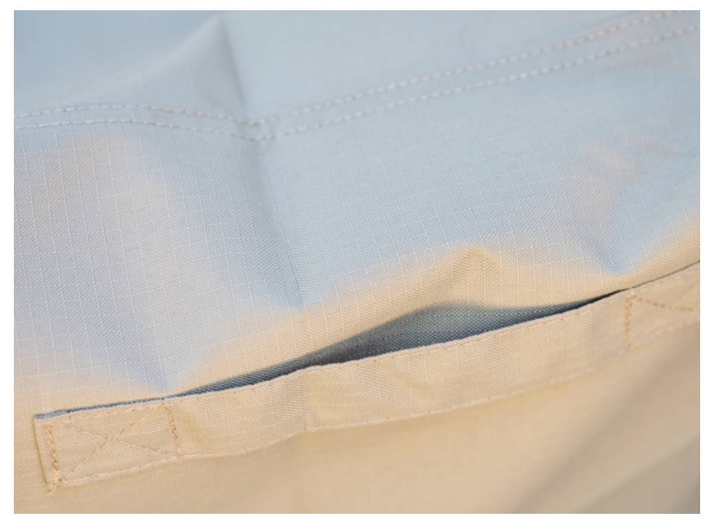 Nahaufnahme eines hellblauen Stoff-Beutels oder einer Tasche mit einer horizontal gesteppten Tasche und offener Naht, dargestellt in weichem Licht.