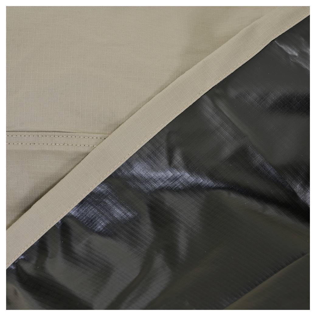 Nahaufnahme eines beigefarbenen Stoffpanels mit diagonaler Naht, das eine glänzende schwarze Oberfläche oder ein glänzendes schwarzes Futter überlappt.