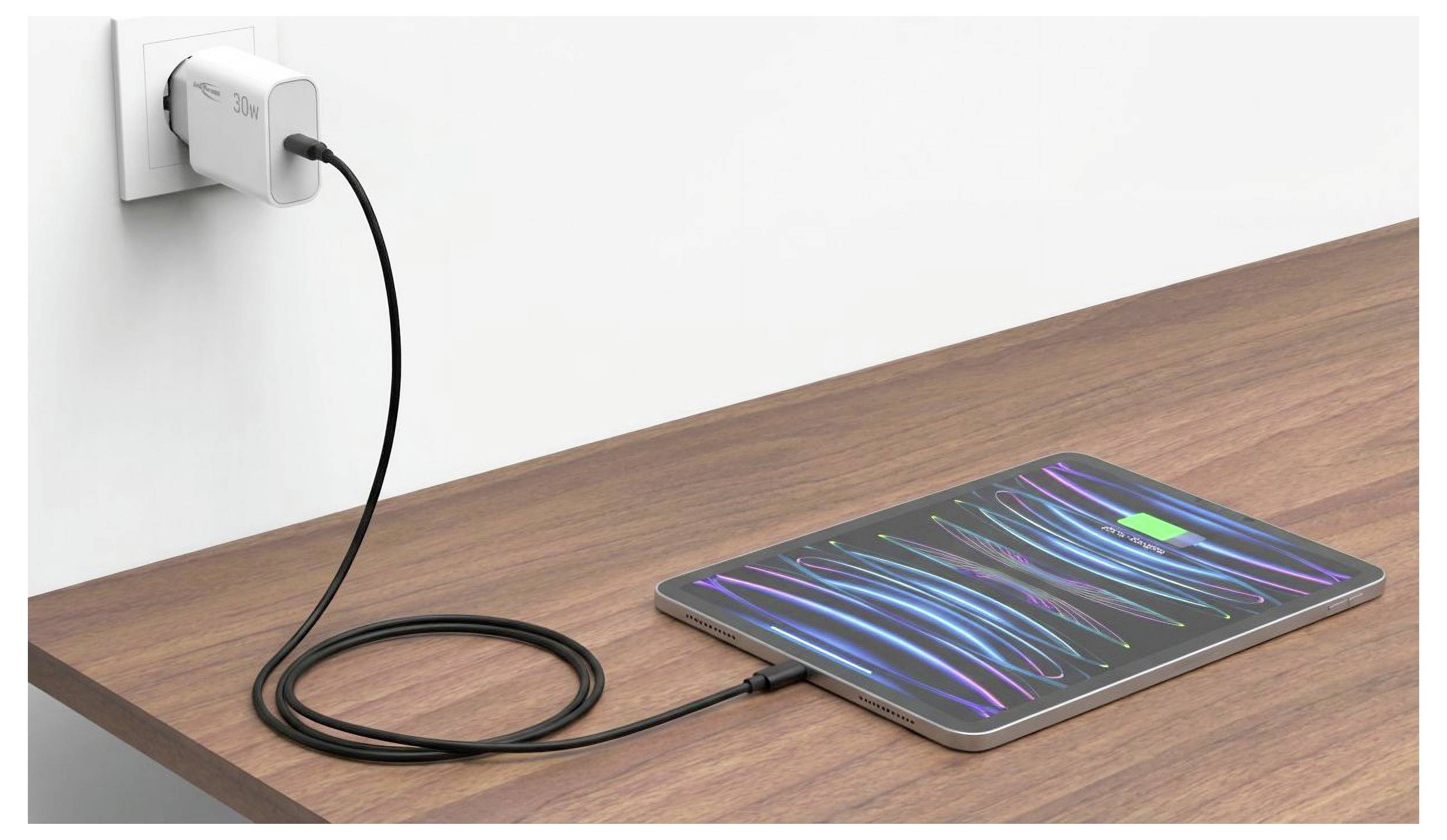 Tablet lädt auf einem Holzschreibtisch, mit einem Kabel mit einer Steckdose verbunden und zeigt einen bunten abstrakten Bildschirm.