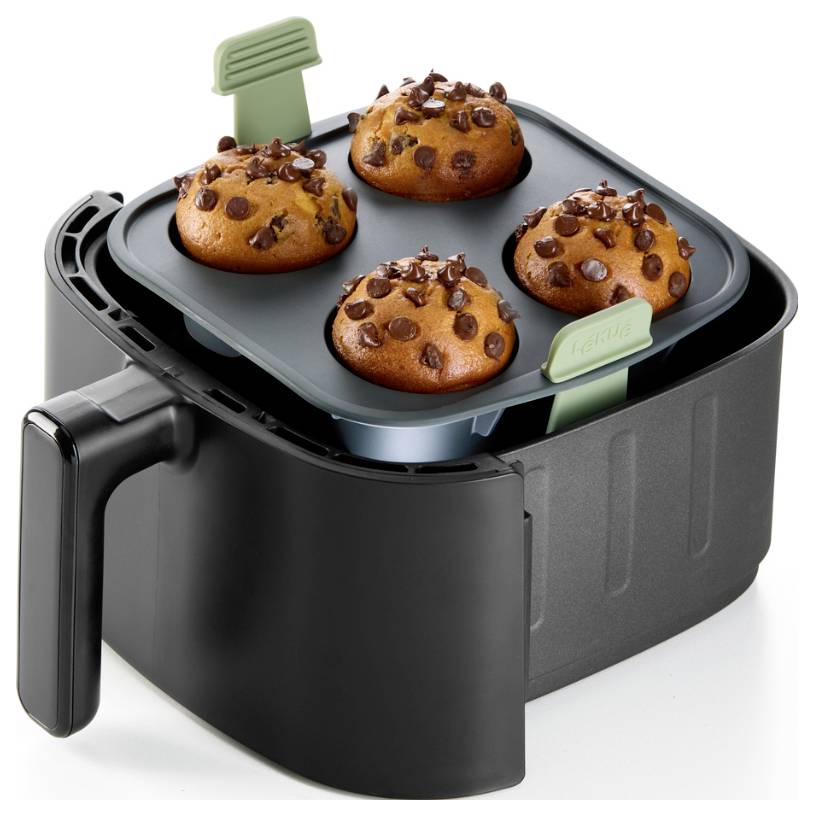 Luftfryer-Korb mit einer antihaftbeschichteten Schale, die vier Schoko-Chip-Muffins hält, von oben fotografiert.