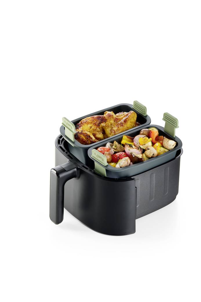 Doppelkorb-Heißluftfritteuse mit zwei Tabletts: eines mit gebratenem Hähnchen, das andere mit gemischtem Gemüse und Kartoffeln.