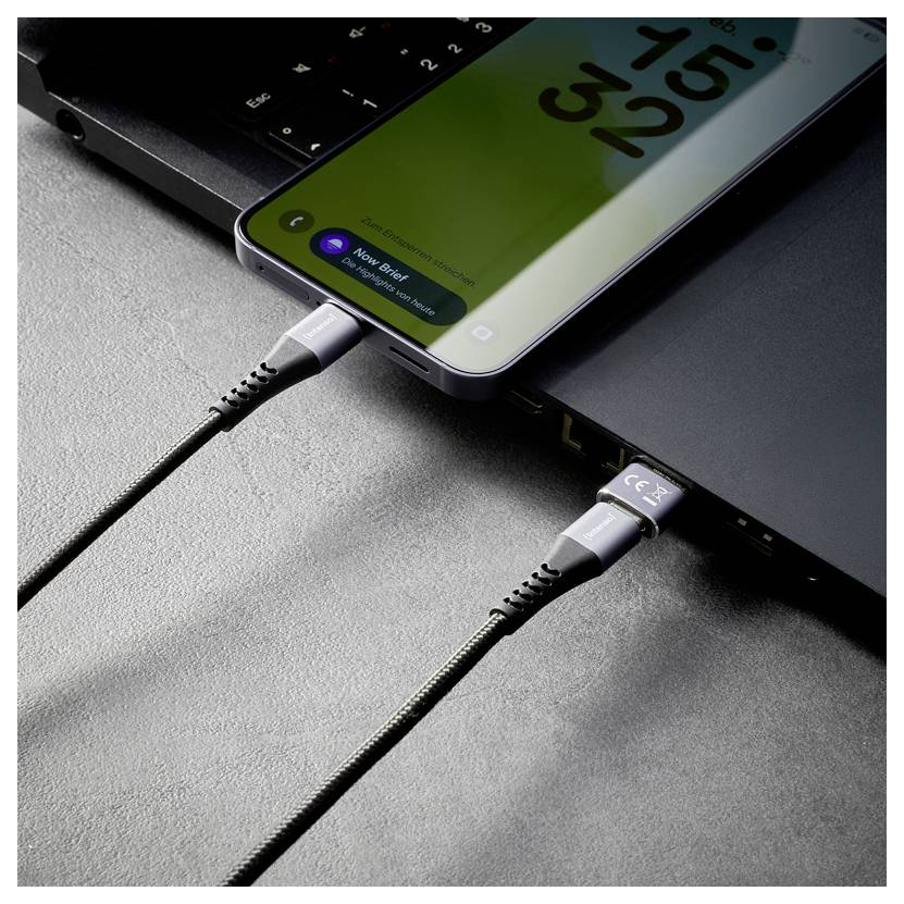 Zwei Smartphones werden über USB-C-Kabel aufgeladen, die mit einem Laptop verbunden sind und zeigen Benachrichtigungen zu kabellosen Kopfhörern auf den Telefonbildschirmen an.