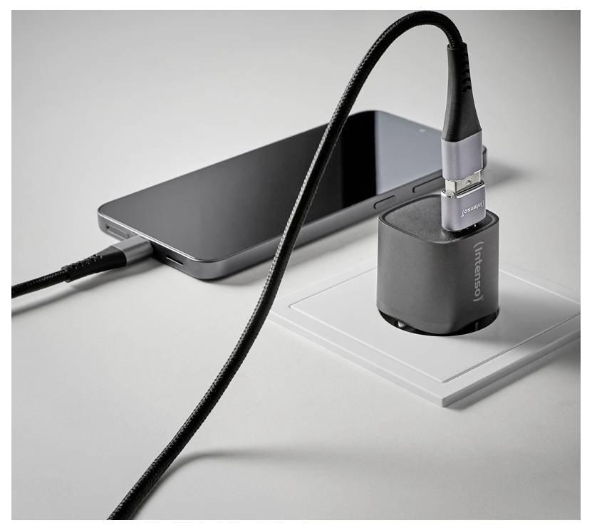 Smartphone, das mit einem Kabel an ein kompaktes graues Ladegerät an einer Wandsteckdose angeschlossen ist, zeigt ein Geräteladesystem.
