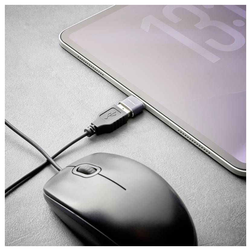 Tablet, das über ein USB-Kabel neben einer schwarzen Kabelraus auf einer grauen Oberfläche verbunden ist, was auf das Aufladen des Geräts oder die Datenübertragung hindeutet.