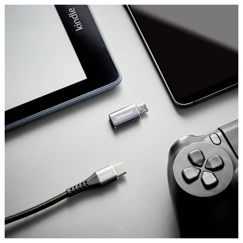 Verschiedene Geräte und Anschlüsse auf einer grauen Oberfläche: Tablet, Smartphone, Game-Controller, USB-C-Kabel und zwei kleine Adapter-Stecker.