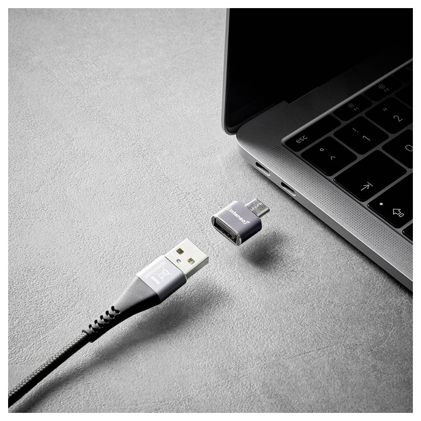 USB-Kabel und kleiner Adapter schweben in der Nähe des USB-C-Anschlusses eines Laptops und deuten auf ein Verbindungs- oder Konvertierungsgerät hin.