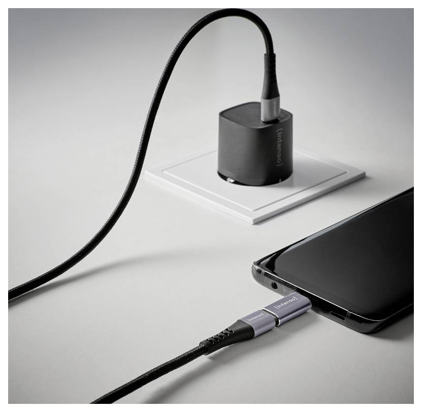 USB-C-Kabel in ein Smartphone gesteckt neben einem kompakten Ladegerät auf einer weißen Oberfläche.