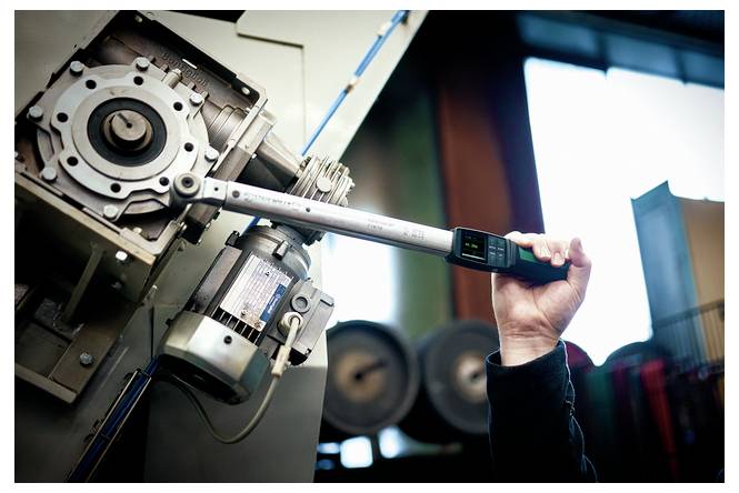 Der Techniker verwendet einen digitalen Drehmomentschlüssel, um ein Maschinenkomponente in einer Industriewerkstatt einzustellen.
