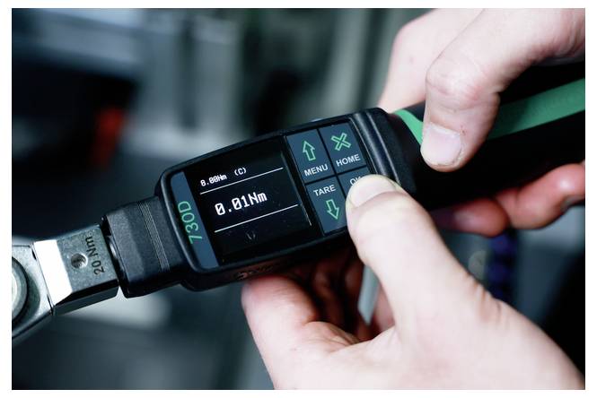 Hände stellen eine digitale Drehmomentschlüssel-Anzeige ein, die 0,81 Nm anzeigt, wird verwendet, um die Anzugskraft an einem Bolzen einzustellen.