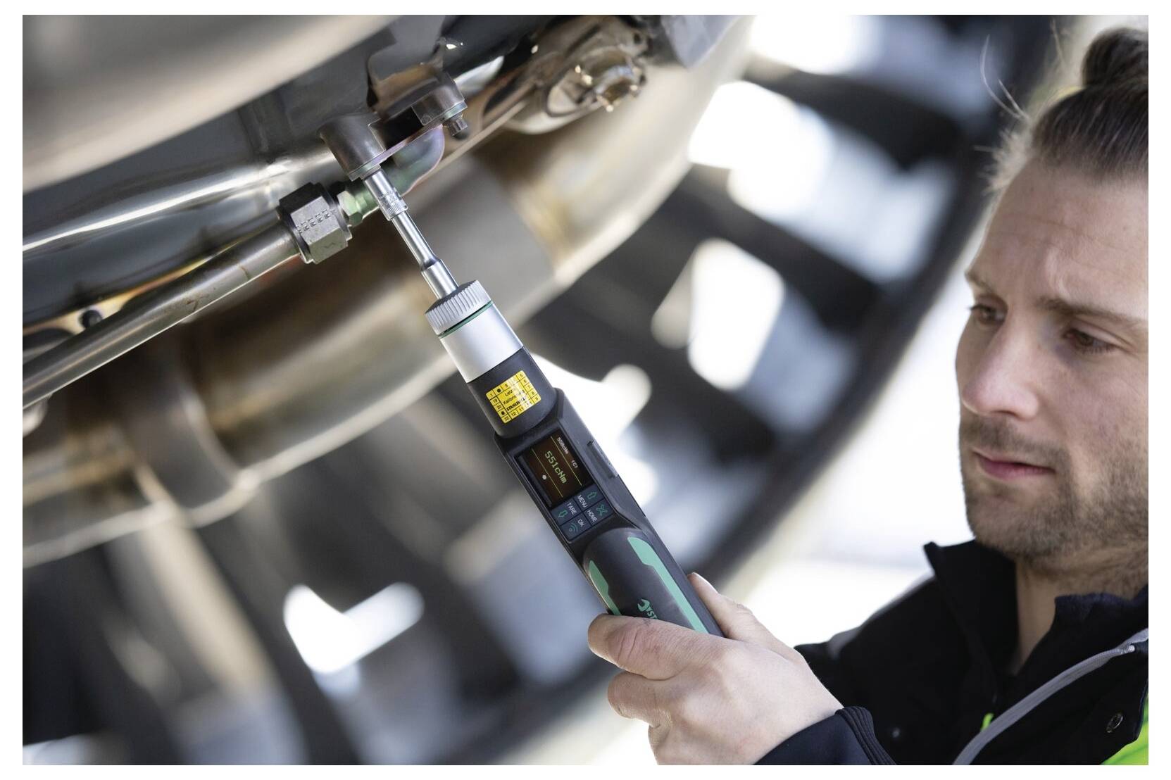 Techniker verwendet einen tragbaren Drehmomentschlüssel zum Anziehen einer Schraube an Industriemaschinen und inspiziert die Ausrüstung genau.