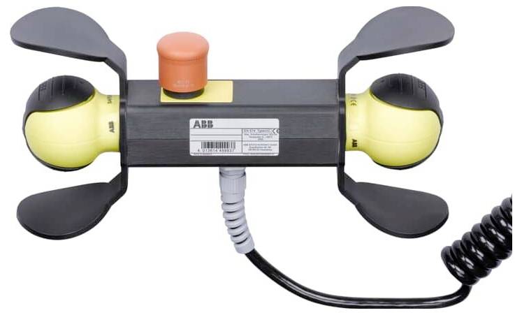 Ein tragbares industrielles Bedienfeld mit zwei gelben joystickähnlichen Griffen, schwarzen Schutzklappen und einem orangefarbenen oberen Knopf, verbunden durch ein spiralförmiges Kabel.