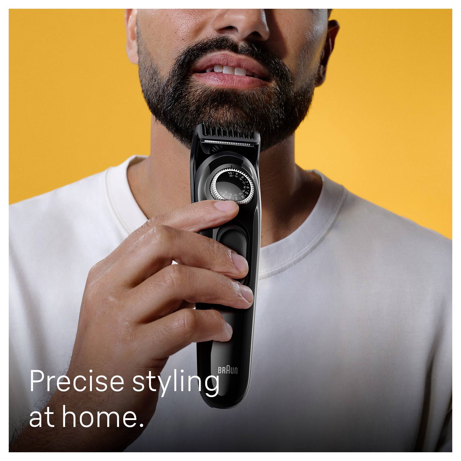 Nahaufnahme eines Mannes, der seinen Bart mit einem elektrischen Trimmer vor einem orangefarbenen Hintergrund trimmt, mit dem Text „Präzises Styling zu Hause.
