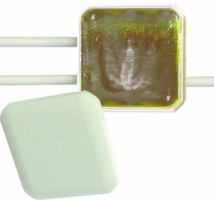 Zwei elektrische Verteilerdosen auf schwarzem Hintergrund, eine offene mit staubigem weißem Innenraum und eine mit geschlossenem violettem Deckel mit der Beschriftung 