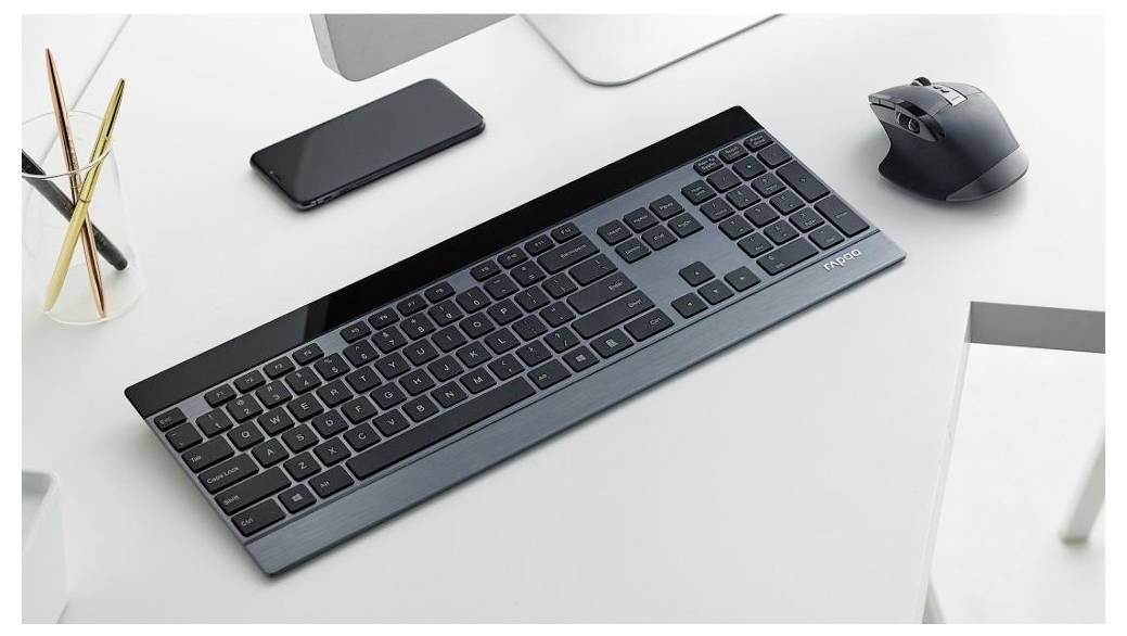 Kabellose Tastatur, Maus und Smartphone auf einem sauberen weißen Schreibtisch mit einem Stifthalter, was auf einen minimalistischen Büroarbeitsplatz hindeutet.