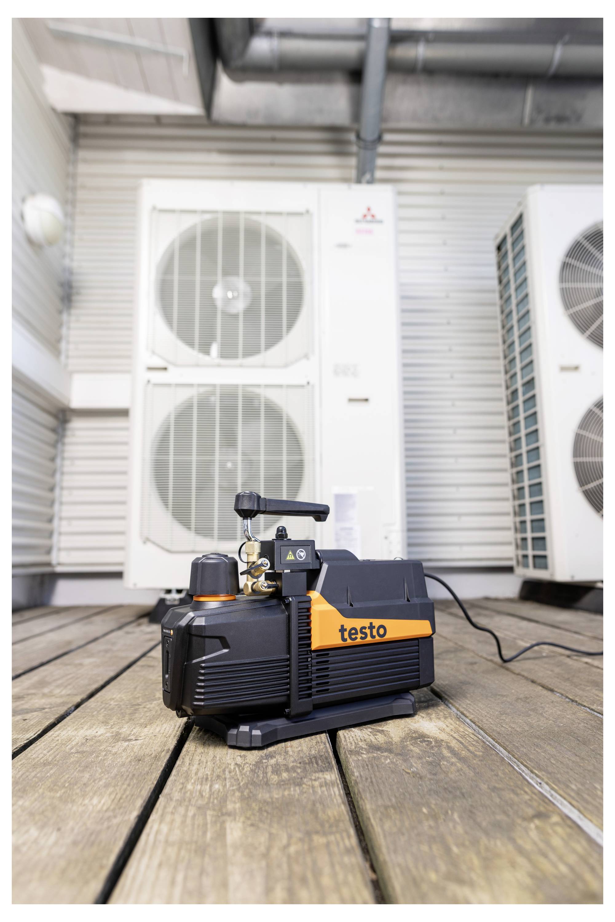 Portable Testo-Vakuumpumpe auf einem Holzdeck vor Außenluftkonditionierungsgeräten.