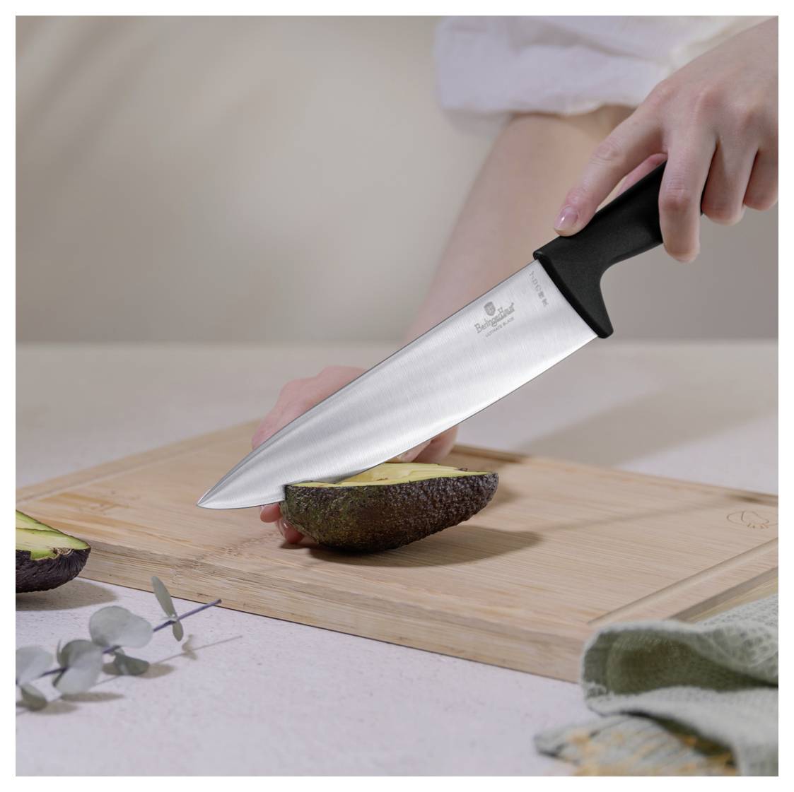 Eine Person schneidet eine Avocado auf einem Holzschneidebrett mit einem Kochmesser in einer Küchenumgebung.