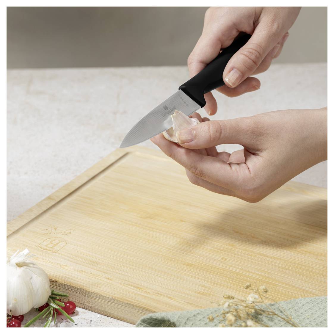 Hände, die ein Messer verwenden, um Knoblauch auf einem hölzernen Schneidebrett zu schälen