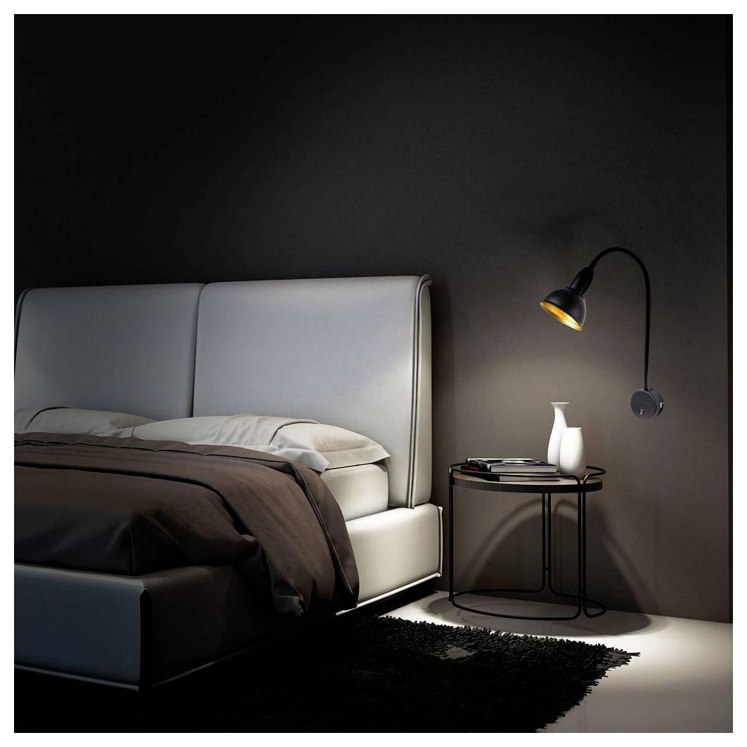 Modernes Schlafzimmer mit einem grau gepolsterten Bett, dunkler Bettwäsche, schwarzem Nachttisch, weißer Vase und wandmontierter Lampe an einer dunklen Wand.