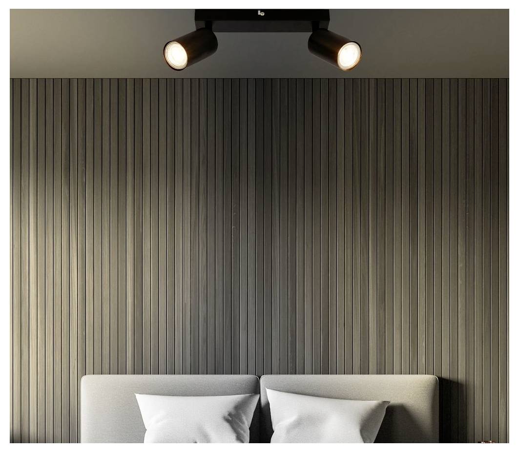 Innenschlafzimmerwand mit vertikaler dunkler Panelverkleidung, zwei leuchtende Deckenspotlights und die Oberseite eines Bettes mit weißen Kissen, die darunter sichtbar sind.